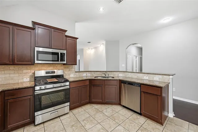 a kitchen with granite countertop a stove microwave and sink