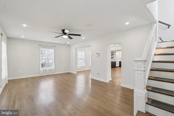 a view of an empty room with wooden floor and a ceiling fan