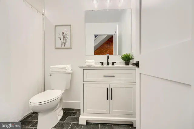 a bathroom with a toilet sink vanity and mirror