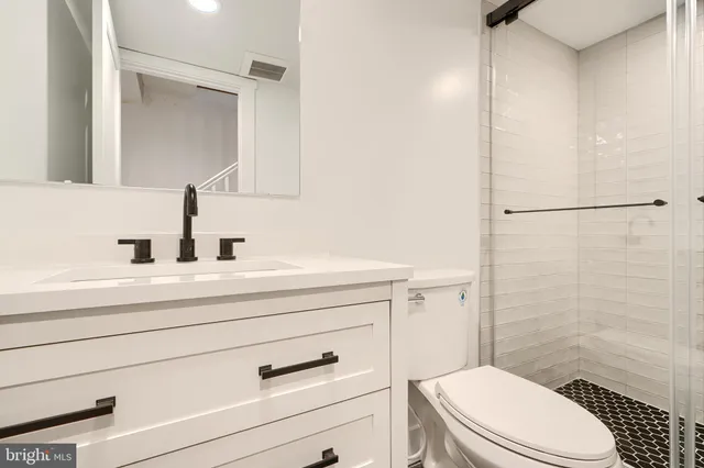 a bathroom with a sink a toilet a mirror and shower