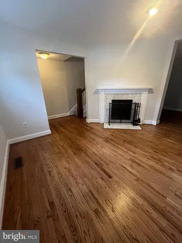 a view of empty room with wooden floor and fireplace
