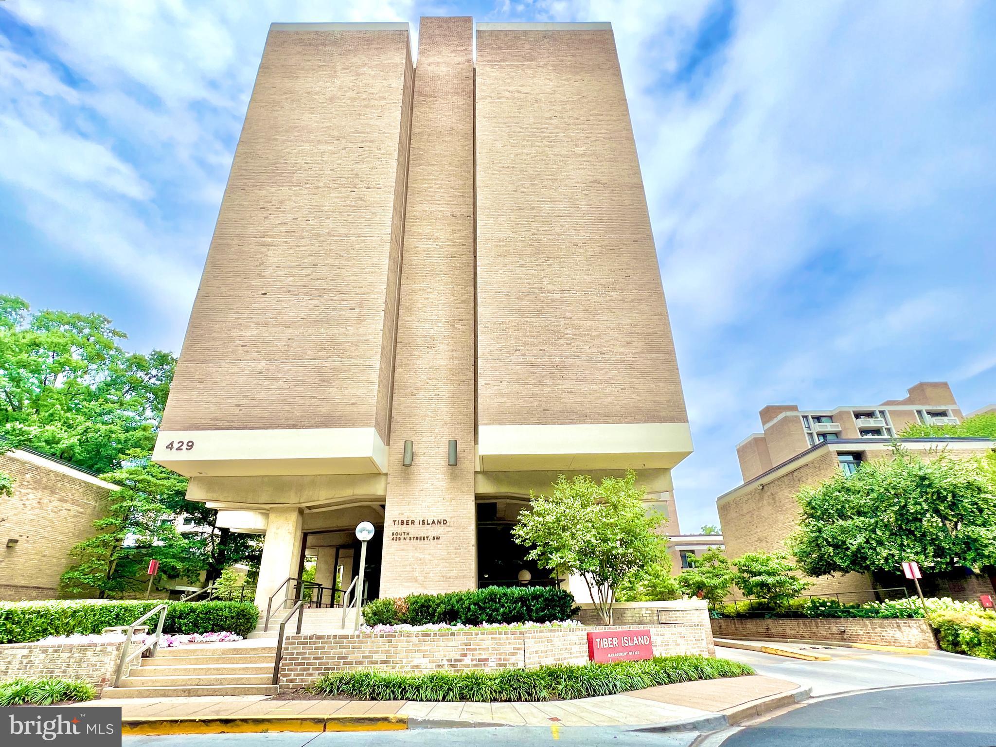 a front view of a multi story residential apartment building with yard and entertaining space