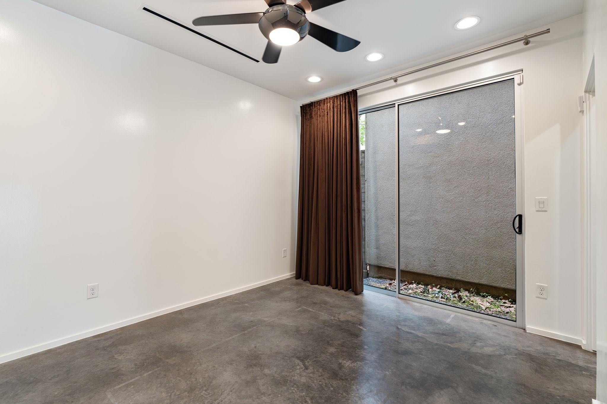 1728 Michigan Street, Unit B Houston, TX 77006 - Photo 20 of 24 The first-floor bedroom is the perfect space for a home office or private guest suite. It features stained concrete floors, a peek at outdoor greenspace, and an added mini split HVAC unit for energy efficiency.
