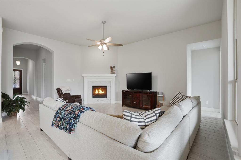 1429 Eclipse Road Aubrey, TX 76227 - Photo 7 of 37 The living room features light-colored flooring, a fireplace with a white mantel, and a ceiling fan