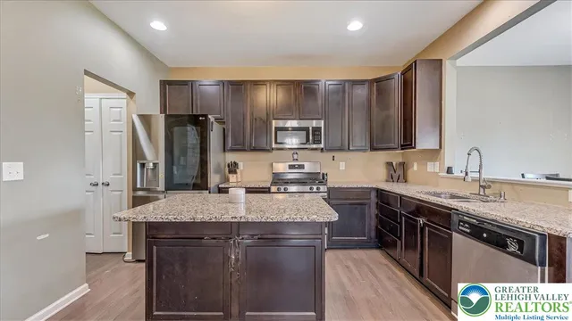 a kitchen with stainless steel appliances granite countertop a sink stove refrigerator and cabinets