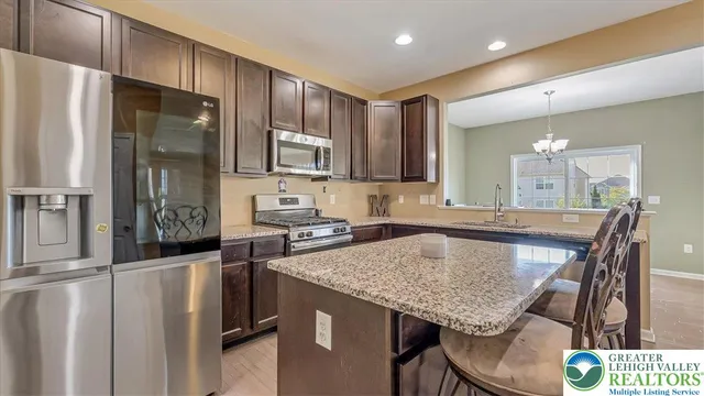 a kitchen with granite countertop kitchen island stainless steel appliances a refrigerator stove microwave and sink