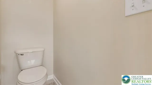 a white toilet sitting next to a white wall