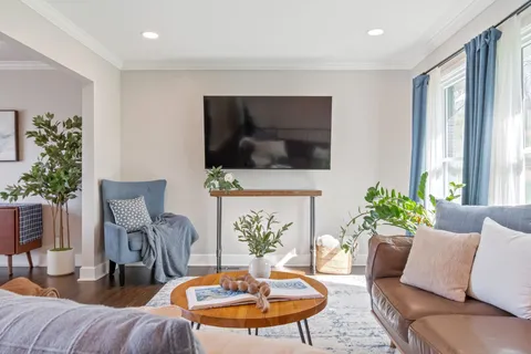 a living room with furniture kitchen view and a wooden floor