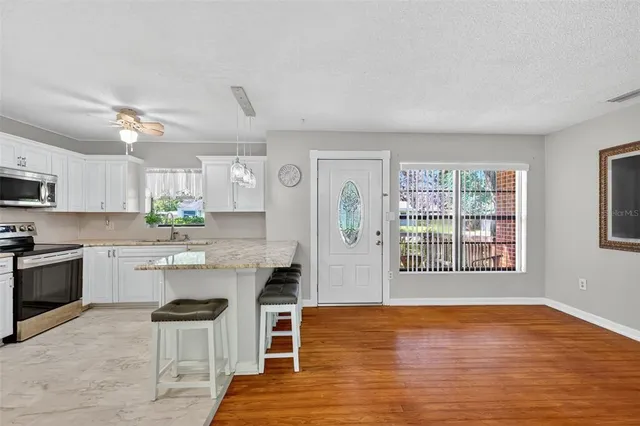 a kitchen with stainless steel appliances a dining table chairs refrigerator and microwave