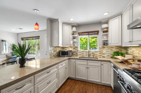 a kitchen with stainless steel appliances kitchen island granite countertop a table chairs and a refrigerator