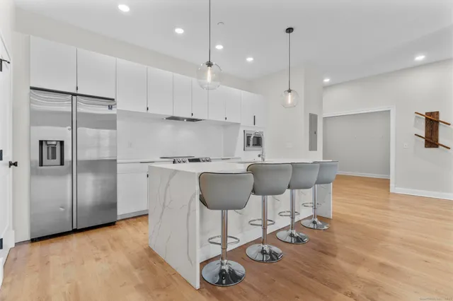 a kitchen with stainless steel appliances granite countertop a refrigerator a stove a sink and a dining table with wooden floor