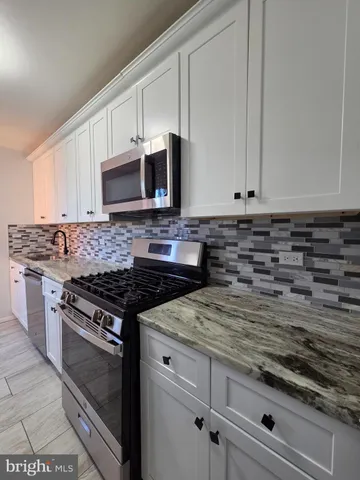 a kitchen with granite countertop white cabinets and stainless steel appliances