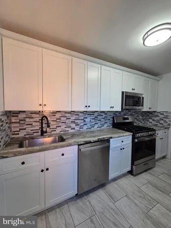 a kitchen with stainless steel appliances granite countertop a sink and cabinets with wooden floor