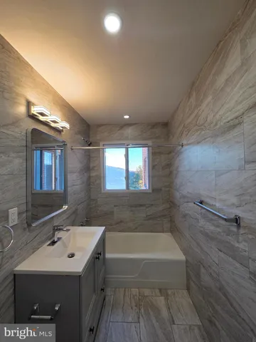 a bathroom with a sink mirror vanity and bathtub