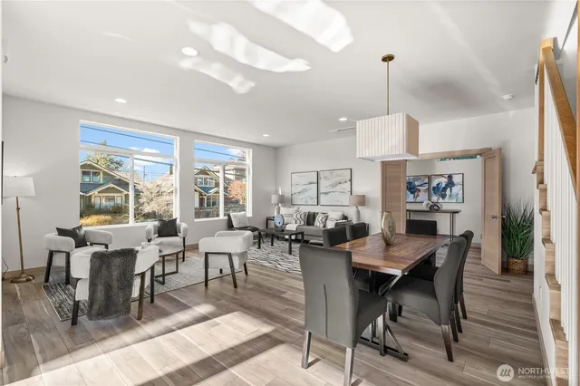 a view of a dining room and livingroom with furniture wooden floor a rug a flat screen tv a painting and a chandelier