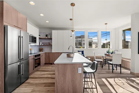 a kitchen with stainless steel appliances kitchen island granite countertop a refrigerator a stove and a dining table with wooden floor