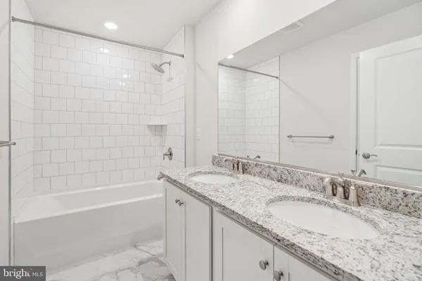a bathroom with a granite countertop double vanity sink and mirror with bathtub