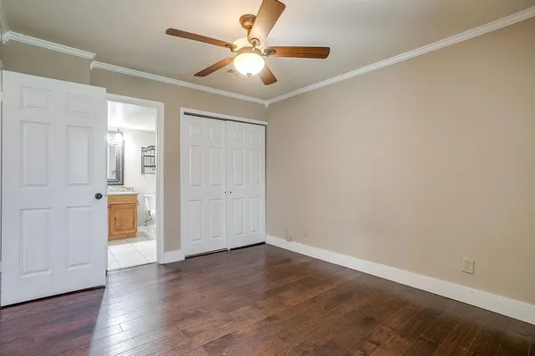 an empty room with wooden floor and a ceiling fan