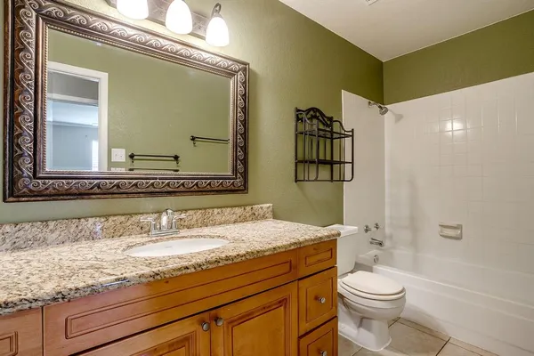 a bathroom with a granite countertop sink a toilet and shower
