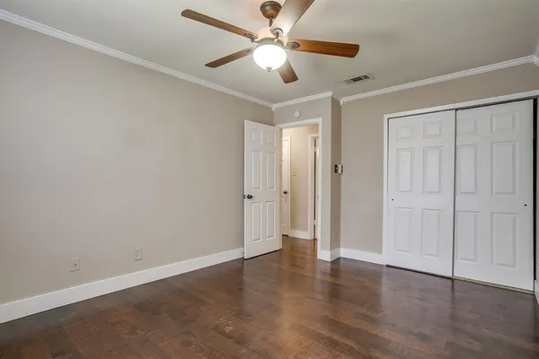 an empty room with wooden floor ceiling fan with window