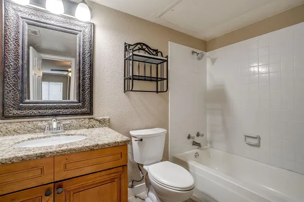a bathroom with a granite countertop toilet a sink and a bathtub