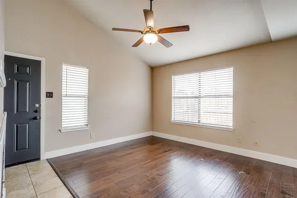 a view of an empty room with a window and wooden floor