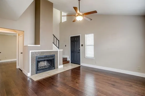a view of an empty room with wooden floor fireplace and a window