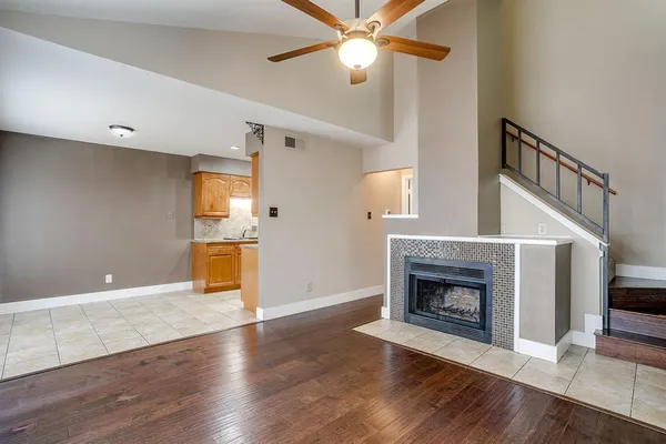 a view of a livingroom with a fireplace a ceiling fan and wooden floor