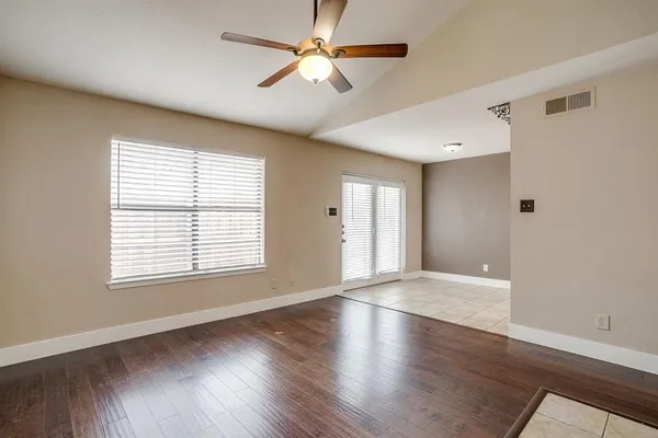 a view of an empty room with window and wooden floor