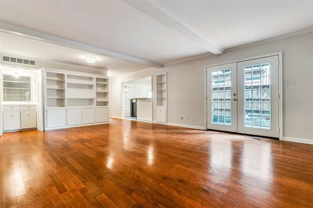 a view of an empty room with a window and wooden floor