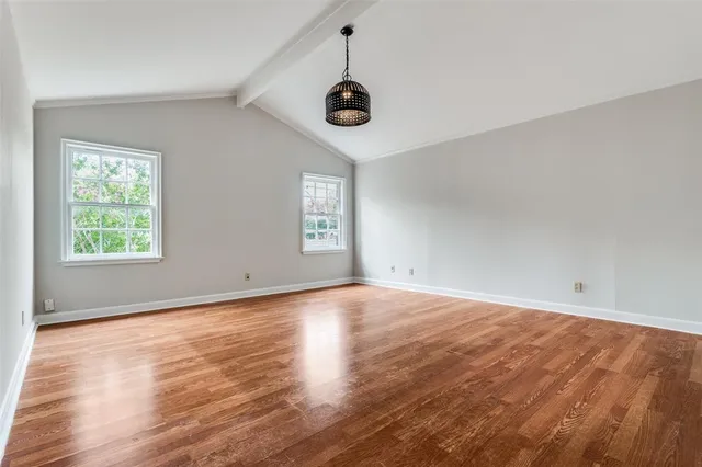 a view of an empty room with window and wooden floor