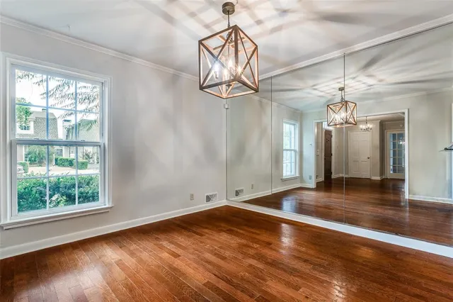 a view of a room with wooden floor chandelier and windows