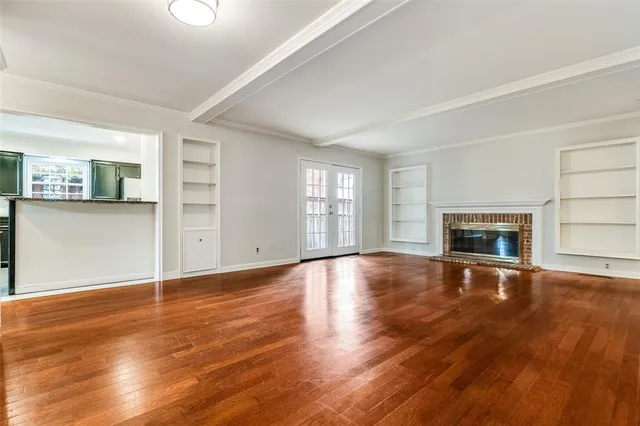 an empty room with wooden floor fireplace and windows