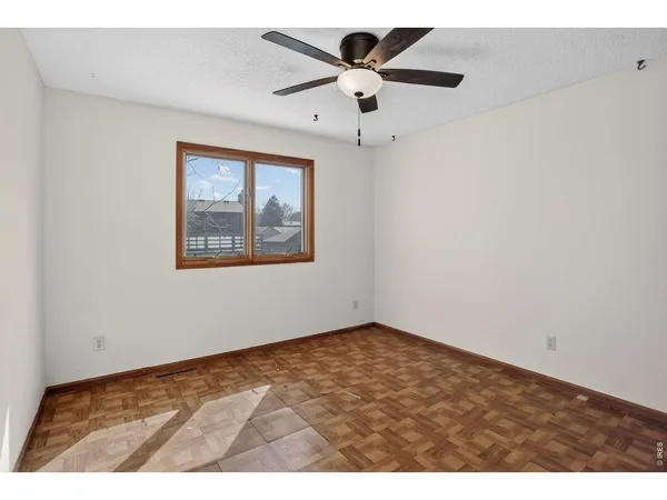 an empty room with a window and a ceiling fan