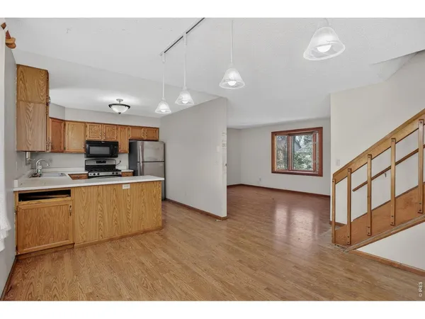 a kitchen with stainless steel appliances granite countertop a stove top oven a sink dishwasher and a microwave oven with wooden floor