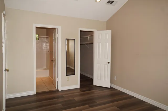 a view of an empty room with wooden floor and closet