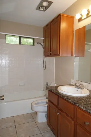 a bathroom with a granite countertop sink a toilet and bathtub