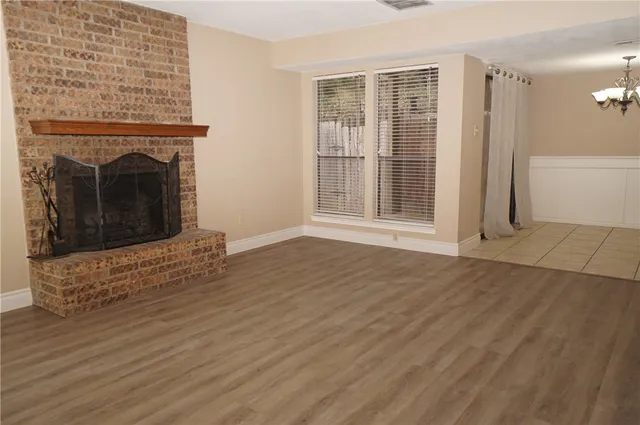 an empty room with wooden floor a fireplace and windows