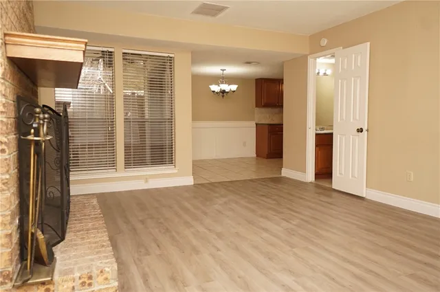 a view of an empty room with wooden floor and a bathroom
