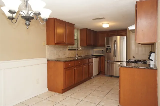 a kitchen with stainless steel appliances granite countertop a refrigerator a sink dishwasher a stove with wooden cabinets