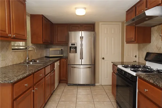 a kitchen with granite countertop a stove sink and refrigerator