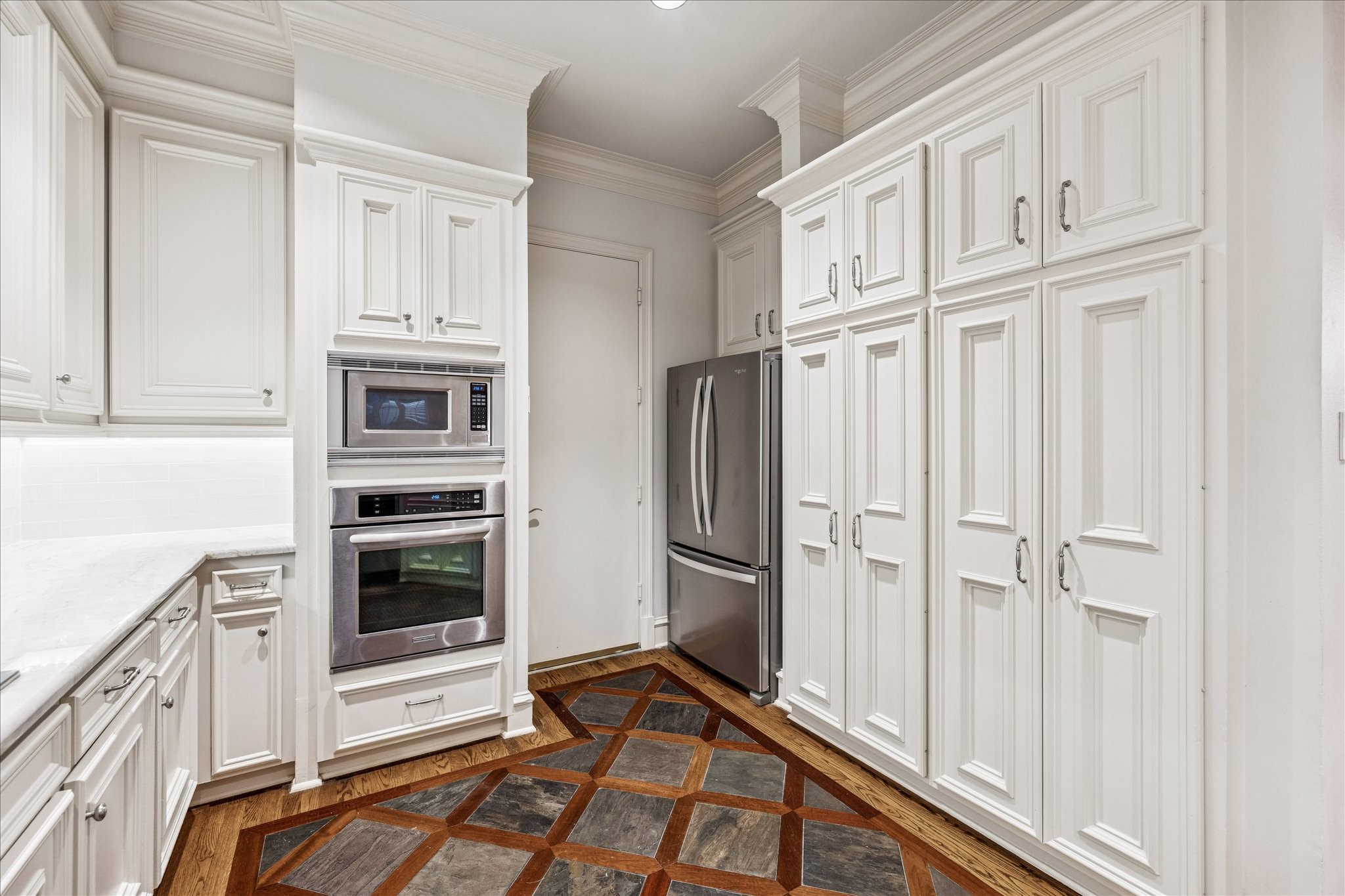 5823 Augusta Court Houston, TX 77057 - Photo 16 of 44 This kitchen has a stainless steel double oven and fridge, and a unique geometric tile floor, combining classic and modern design elements.