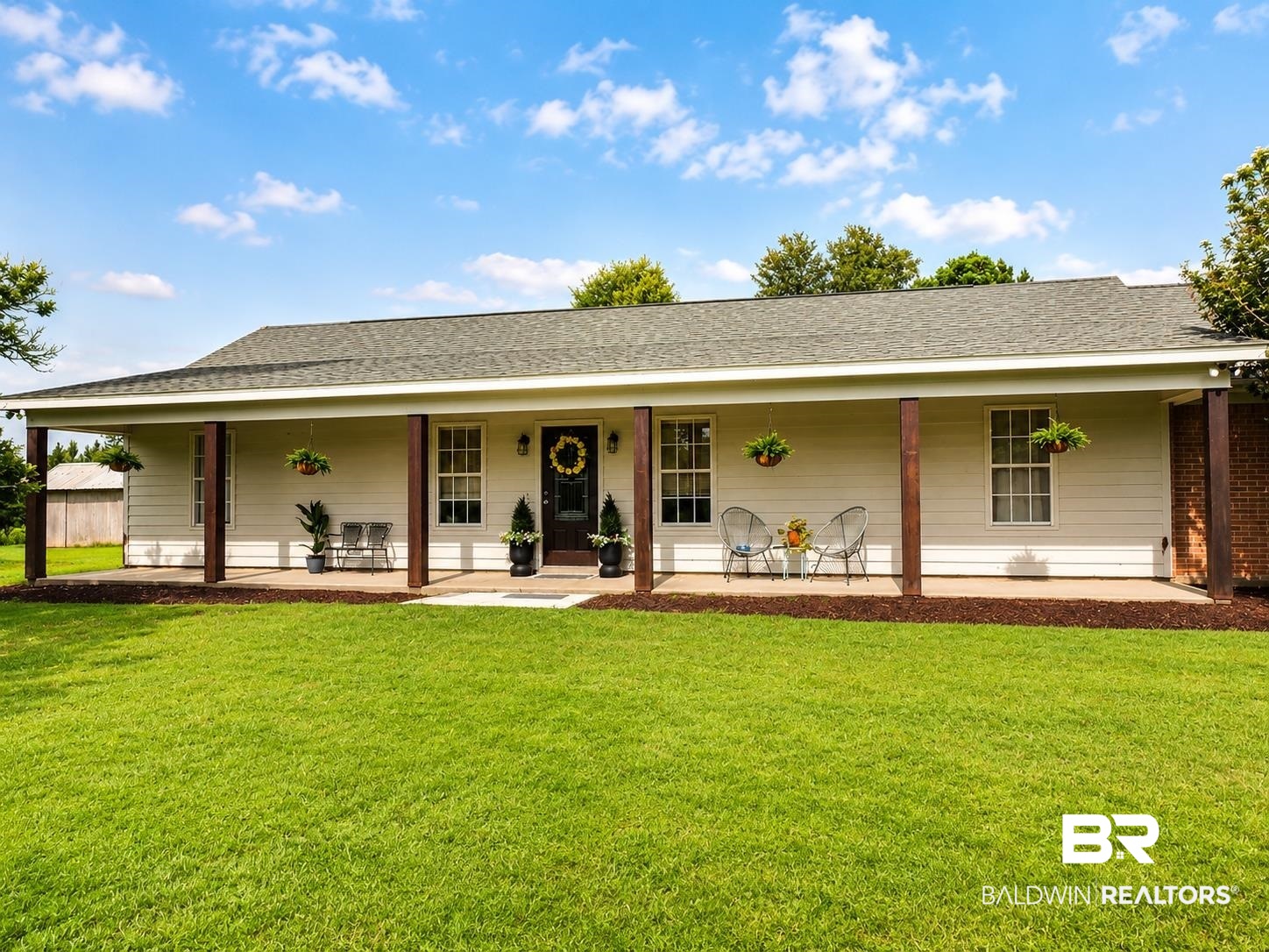 21733 Sedlack Road Silverhill, AL 36576 - Photo 3 of 22 Ranch-style residence featuring a covered front porch with wood-finish posts, white siding, and a dark entry door