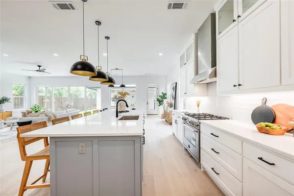 a kitchen with stainless steel appliances granite countertop a sink a stove and a wooden floors