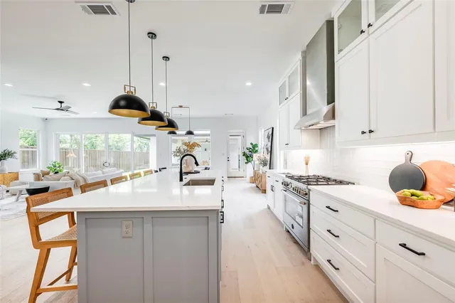 a kitchen with stainless steel appliances granite countertop a sink a stove and a wooden floors