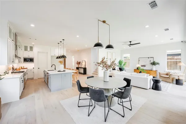 a view of a dining room and livingroom with furniture wooden floor a rug a flat screen tv a painting and a chandelier