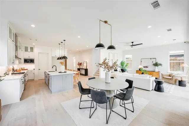 a view of a dining room and livingroom with furniture wooden floor a rug a flat screen tv a painting and a chandelier