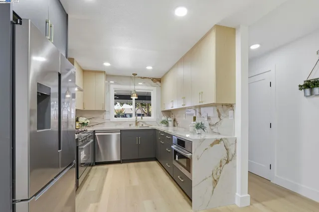 a kitchen with stainless steel appliances granite countertop a sink and a refrigerator