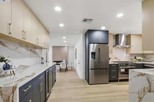 a kitchen with stainless steel appliances granite countertop a refrigerator a stove a sink a dining table and chairs with wooden floor