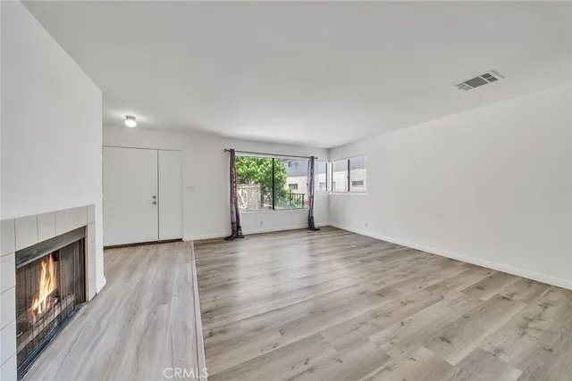 an empty room with wooden floor fireplace and windows